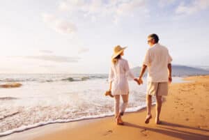 Senior couple enjoys walk on the beach after taking care of vein issues.