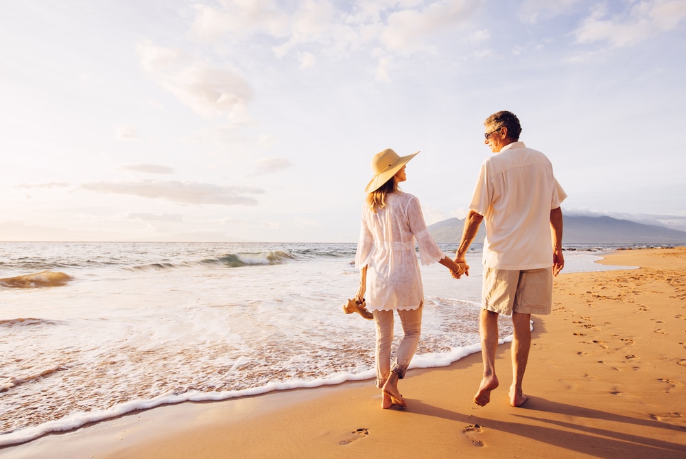 Senior couple enjoys walk on the beach after taking care of vein issues.