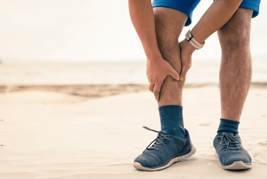 Senior man grabs his legs in pain while out for a walk