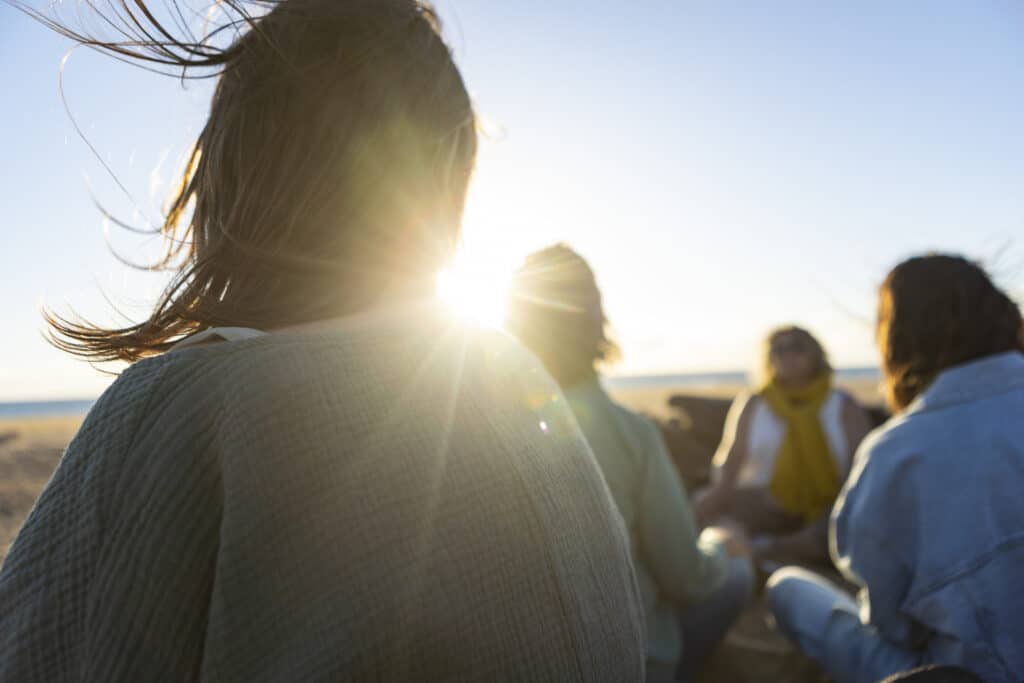 Women meditating together at the beach during a spiritual retreat iStock 2189324442