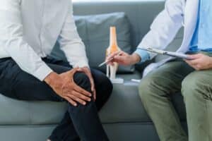 Patient holds knee during consultation about chronic knee pain treatment options.